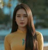 a woman with long hair wearing a yellow dress